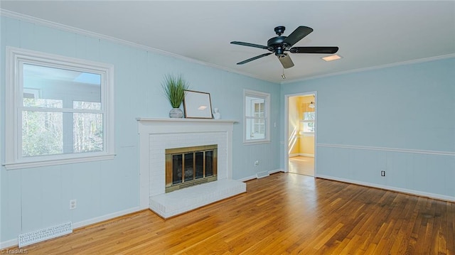 unfurnished living room with ceiling fan, wood-type flooring, ornamental molding, and a fireplace