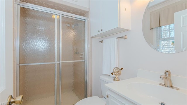 bathroom featuring toilet, a shower with shower door, and vanity