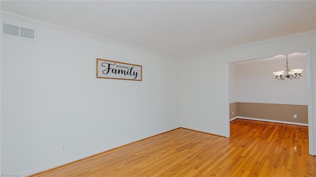 empty room featuring a chandelier, ornamental molding, and wood-type flooring