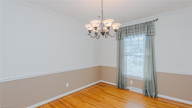 empty room featuring an inviting chandelier, a healthy amount of sunlight, hardwood / wood-style floors, and crown molding