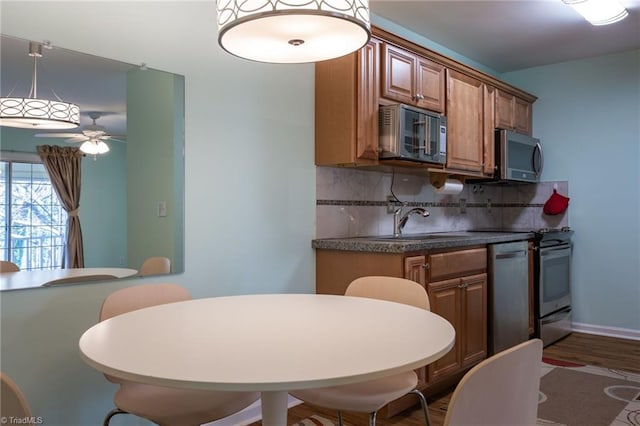 kitchen with appliances with stainless steel finishes, decorative light fixtures, sink, and decorative backsplash