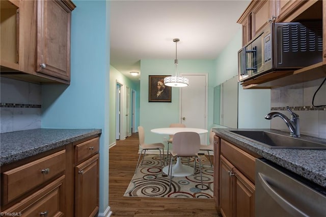 kitchen featuring stainless steel appliances, sink, dark wood-type flooring, and backsplash