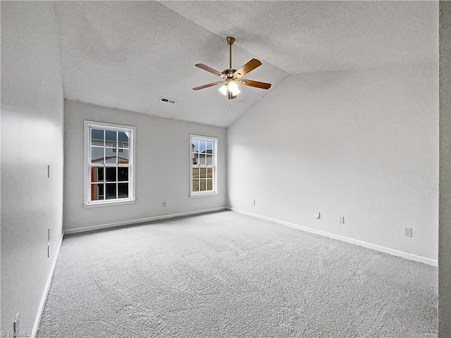 unfurnished room with vaulted ceiling, carpet, and a textured ceiling