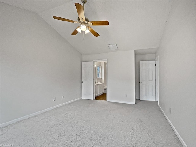 unfurnished bedroom featuring carpet floors, vaulted ceiling, ceiling fan, and ensuite bathroom