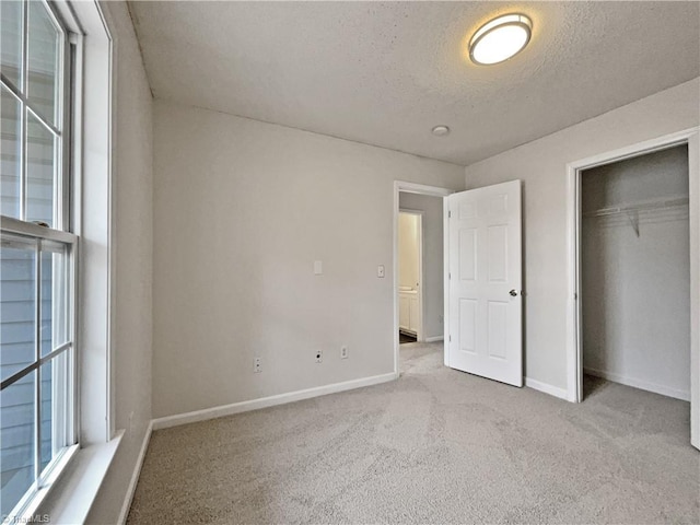 unfurnished bedroom with light colored carpet, a textured ceiling, and a closet