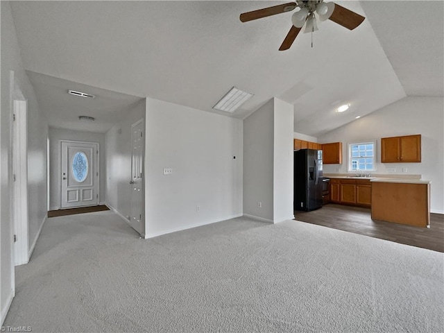 unfurnished living room featuring ceiling fan, carpet flooring, sink, and vaulted ceiling