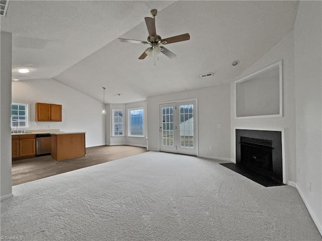 unfurnished living room featuring sink, vaulted ceiling, a textured ceiling, ceiling fan, and carpet