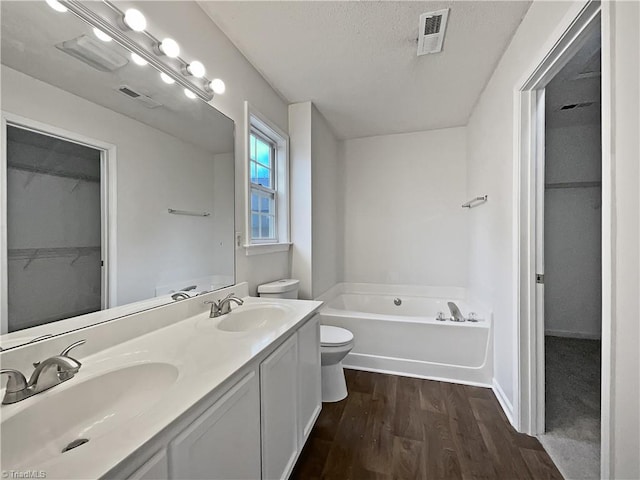 bathroom with hardwood / wood-style floors, a bathtub, vanity, a textured ceiling, and toilet