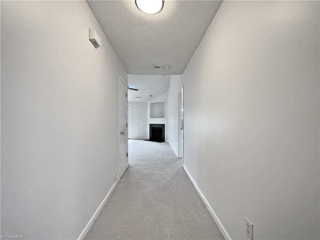 hall featuring light carpet and a textured ceiling