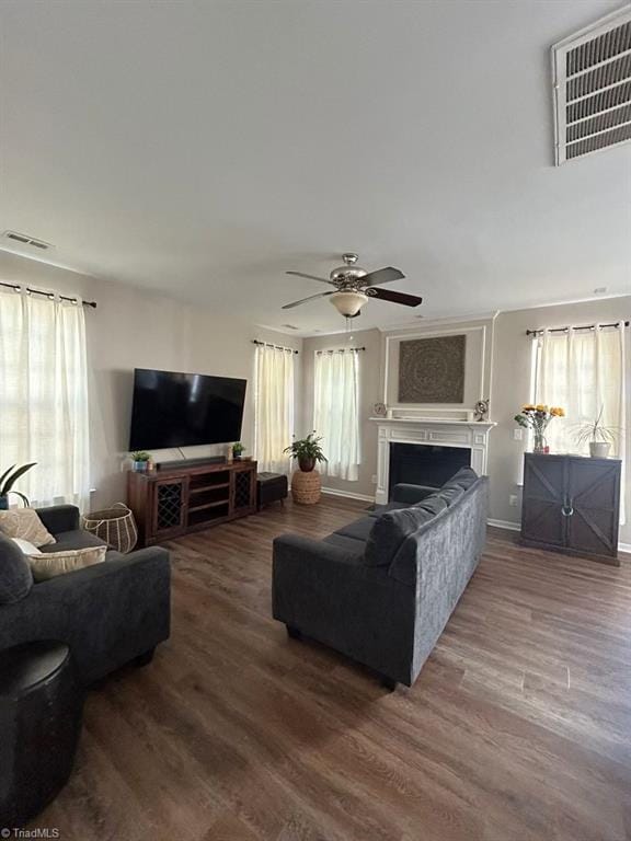 living room featuring ceiling fan, a large fireplace, and hardwood / wood-style flooring