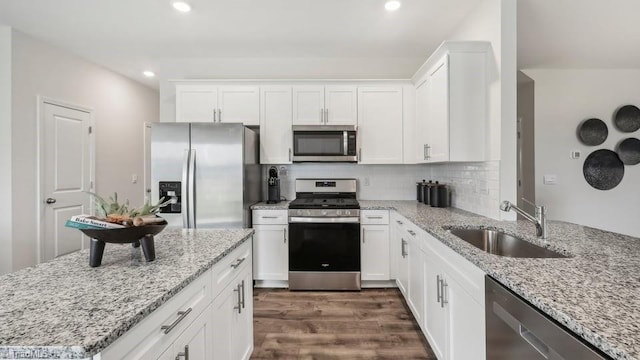kitchen with a sink, white cabinetry, appliances with stainless steel finishes, dark wood-style floors, and decorative backsplash
