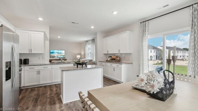 kitchen with white cabinetry, a kitchen island, stainless steel refrigerator with ice dispenser, and visible vents