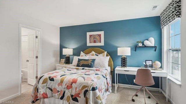 carpeted bedroom featuring ensuite bath, baseboards, and visible vents