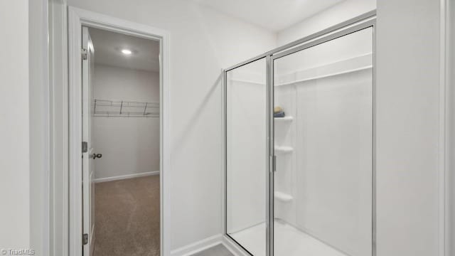 full bathroom featuring a shower stall, baseboards, and a spacious closet