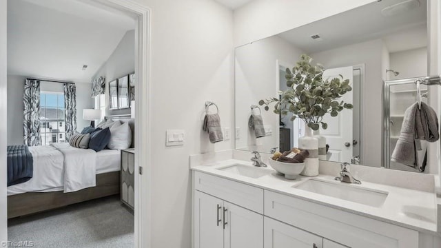 ensuite bathroom with a shower with door, double vanity, connected bathroom, and a sink