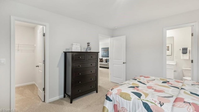 bedroom with a closet, baseboards, a spacious closet, and light colored carpet