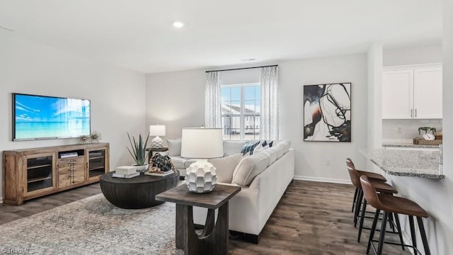 living room featuring dark wood finished floors, baseboards, and recessed lighting