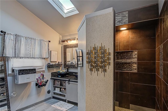 bathroom with vaulted ceiling with skylight, sink, and tile patterned floors