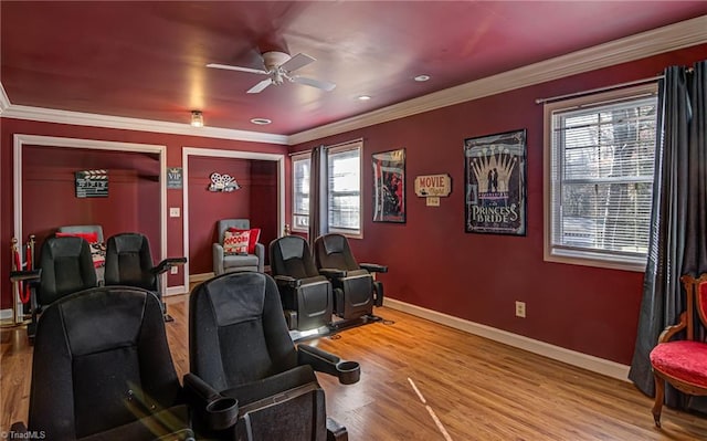 home theater room with ceiling fan, light hardwood / wood-style flooring, a healthy amount of sunlight, and ornamental molding