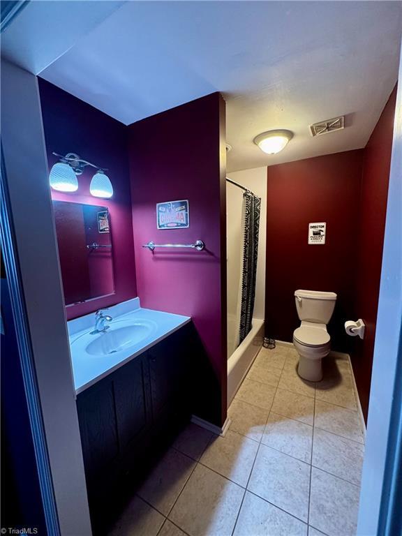 full bathroom featuring tile patterned floors, vanity, toilet, and shower / bath combo with shower curtain