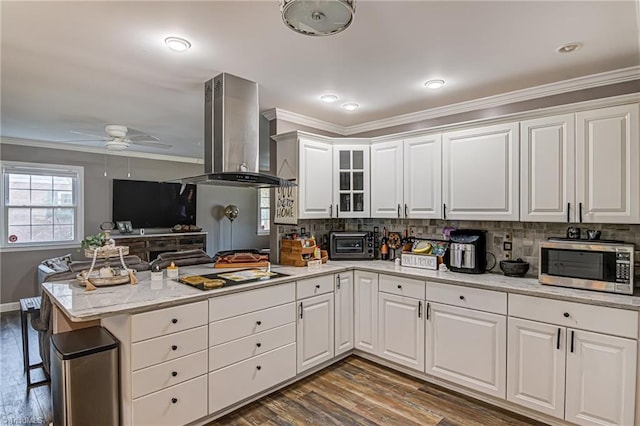 kitchen with dark wood-type flooring, white cabinets, ceiling fan, kitchen peninsula, and island exhaust hood