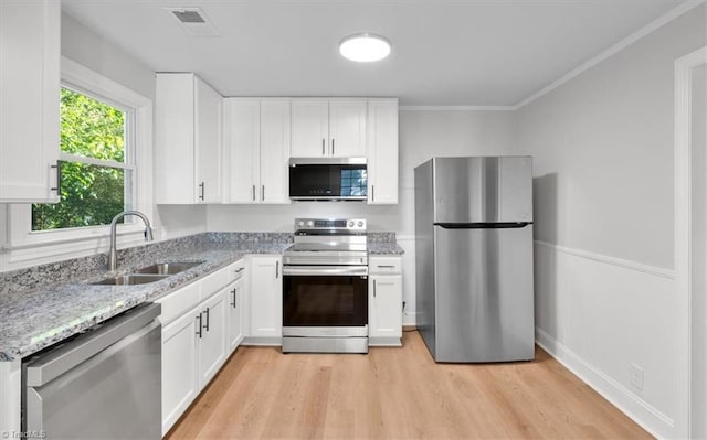 kitchen with appliances with stainless steel finishes, a sink, and white cabinetry