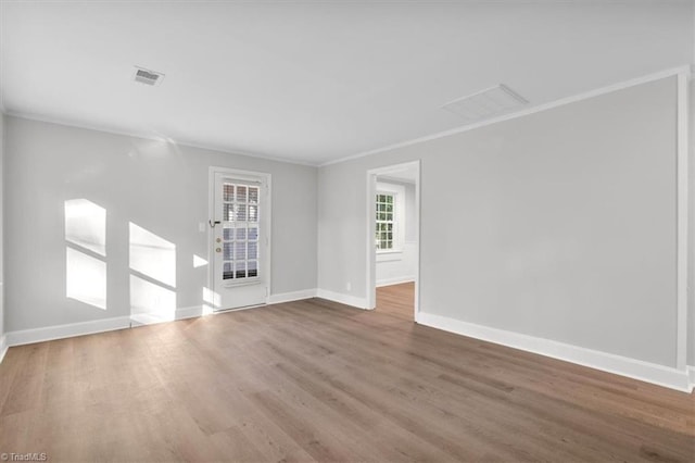 interior space with ornamental molding, wood finished floors, visible vents, and baseboards