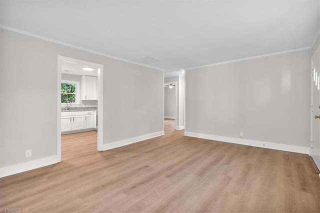 unfurnished living room with baseboards, a sink, light wood-style flooring, and crown molding