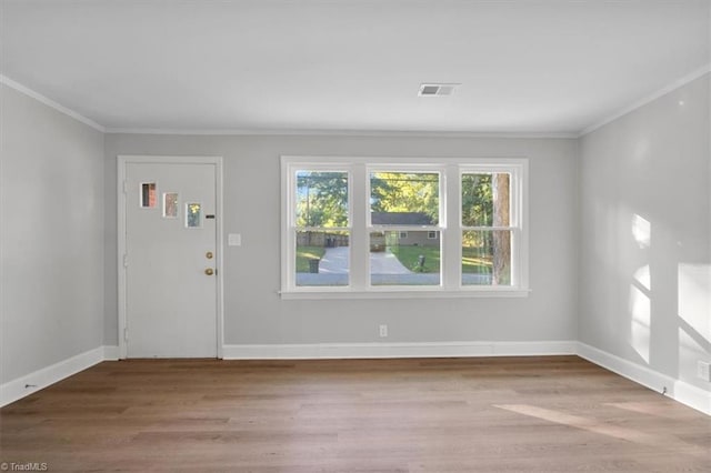 foyer entrance with ornamental molding, wood finished floors, visible vents, and baseboards