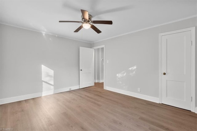 empty room featuring ceiling fan, baseboards, crown molding, and wood finished floors