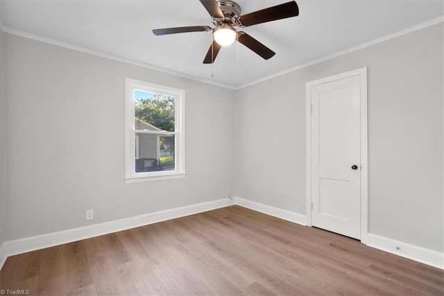 spare room with a ceiling fan, crown molding, baseboards, and wood finished floors