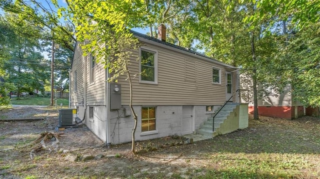 rear view of property with a chimney and central AC