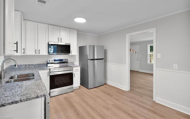 kitchen featuring light stone counters, visible vents, appliances with stainless steel finishes, white cabinetry, and a sink