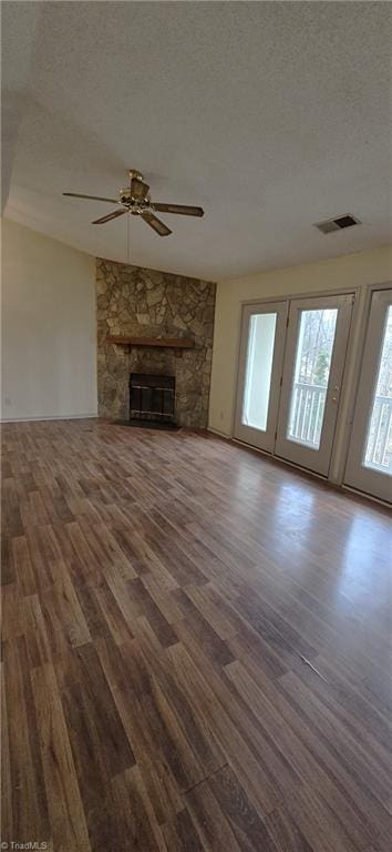 unfurnished living room with ceiling fan, dark wood-type flooring, a textured ceiling, and a fireplace