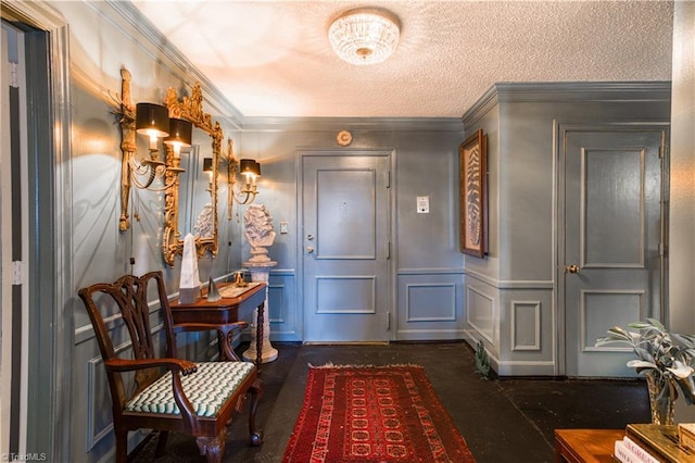 foyer entrance featuring a textured ceiling, a decorative wall, a wainscoted wall, and ornamental molding