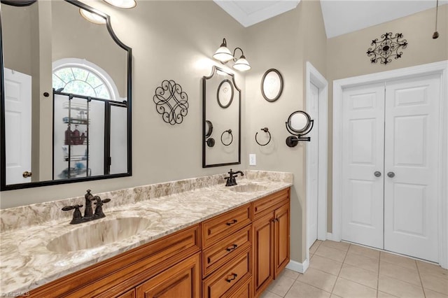 full bath with double vanity, a sink, tile patterned floors, and baseboards