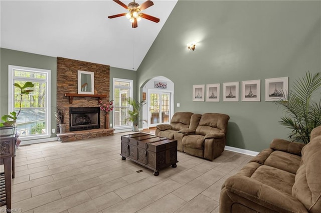 living room featuring a fireplace, a wealth of natural light, ceiling fan, and arched walkways