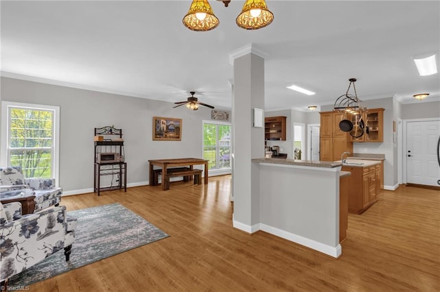 kitchen with light wood-type flooring, baseboards, ornamental molding, and a sink