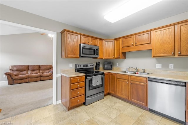 5803 Sycamore Glen Rd, Greensboro, NC 27405 - kitchen featuring stainless steel appliances, light countertops, light carpet, brown cabinets, and open floor plan