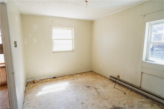unfurnished room with baseboard heating, a textured ceiling, and baseboards