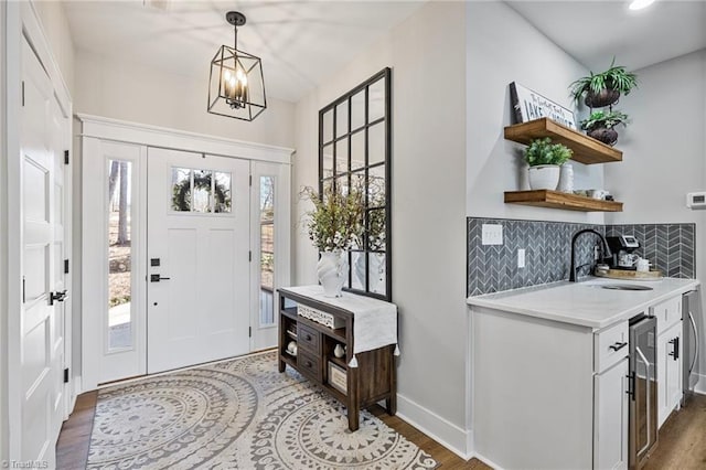 foyer entrance with sink, an inviting chandelier, beverage cooler, and dark hardwood / wood-style floors