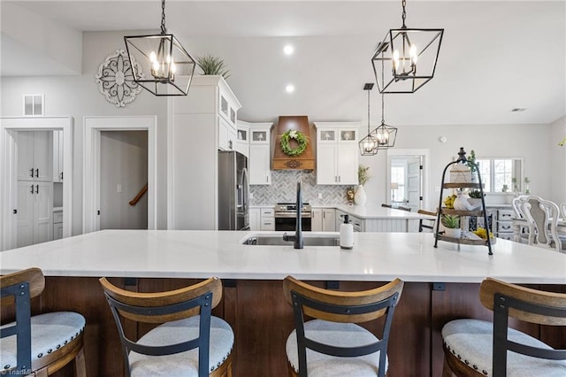 kitchen with white cabinetry, hanging light fixtures, stainless steel fridge, and a chandelier