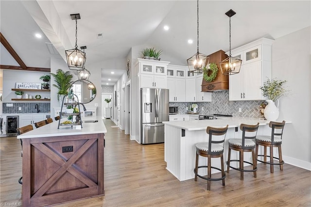 kitchen with a breakfast bar, white cabinetry, hanging light fixtures, stainless steel appliances, and light hardwood / wood-style floors