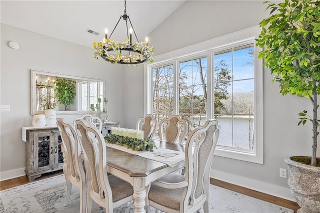 dining area with an inviting chandelier, lofted ceiling, and wood-type flooring