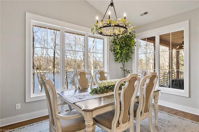 dining area with wood-type flooring, a chandelier, and vaulted ceiling