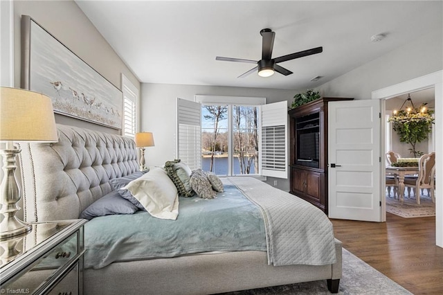 bedroom featuring dark hardwood / wood-style floors and ceiling fan with notable chandelier