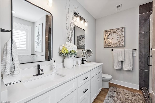 bathroom with an enclosed shower, hardwood / wood-style floors, vanity, and toilet