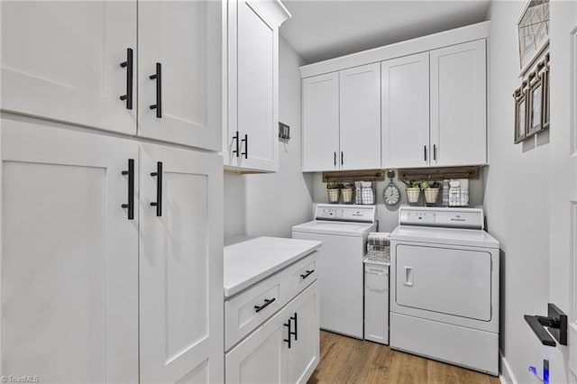 laundry area with cabinets, washer and clothes dryer, and light hardwood / wood-style floors