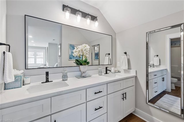 bathroom featuring hardwood / wood-style flooring, vanity, toilet, and vaulted ceiling