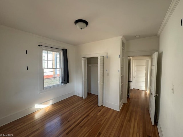 unfurnished bedroom with dark hardwood / wood-style flooring, crown molding, and a closet